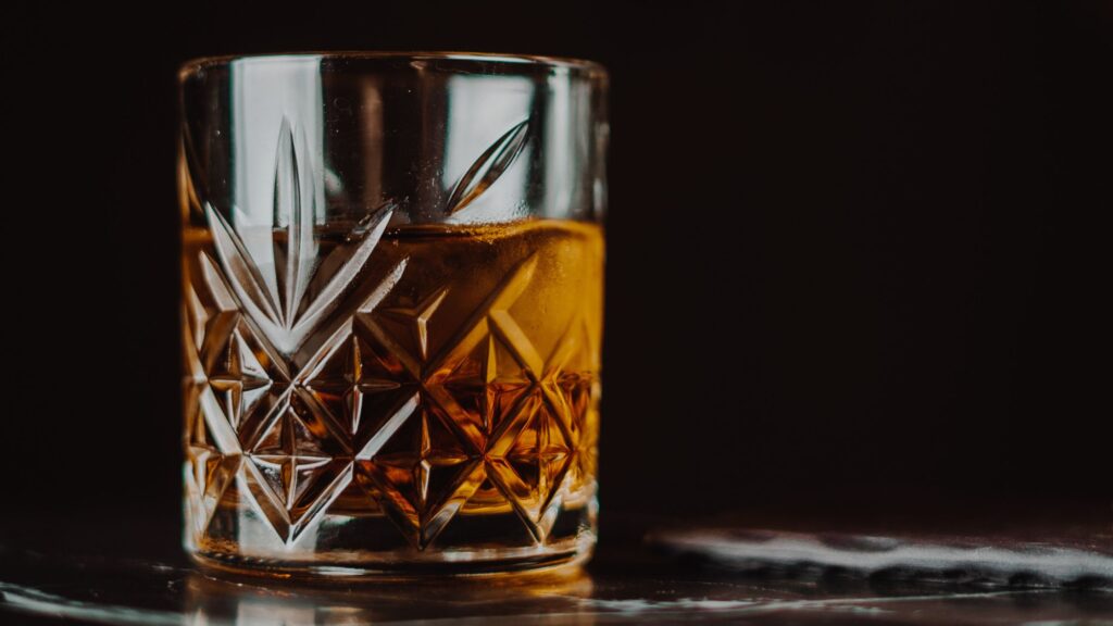 A glass of whiskey on a countertop.