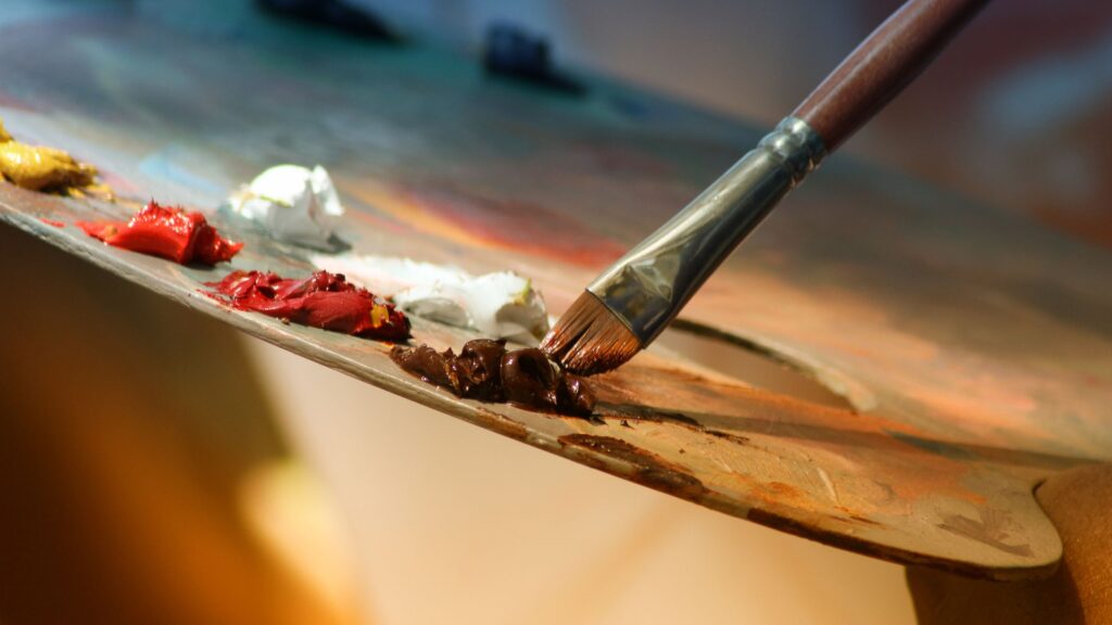 A photo of paint and a paintbrush being dipped in the paint.